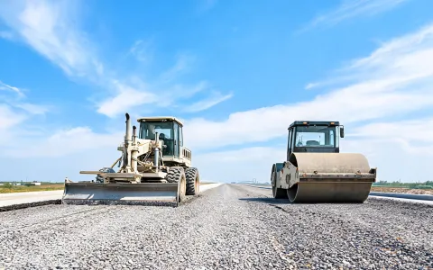 Motor grader and roller on base course